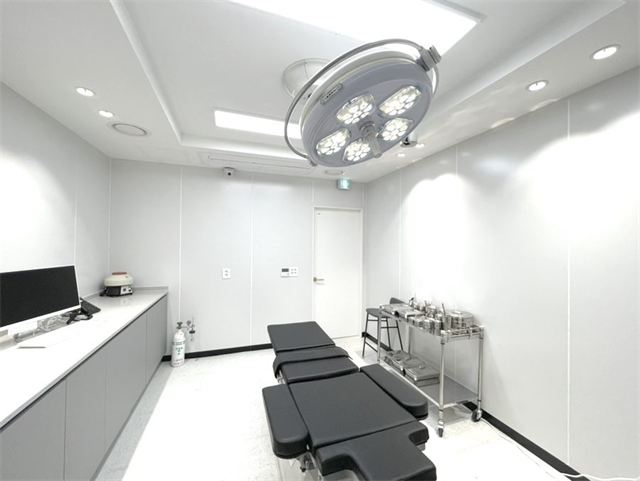 Procedure room with an operating table and surgical light at Ahn Sung Min Plastic Surgery