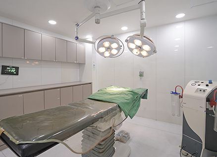 Room with an operating table and surgical lights at BBAE Clinic