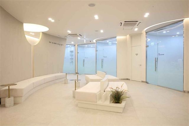 Patient lounge with white benches and frosted-glass room doors at Re:Berry Skin Clinic Yeongjong