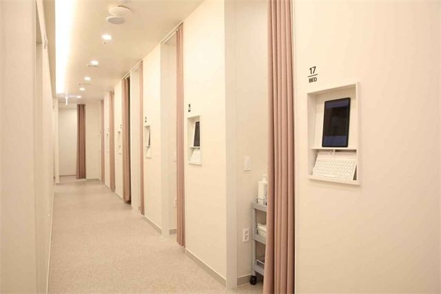 Corridor of curtained treatment rooms with numbered beds at Re:Berry Skin Clinic Yeongjong