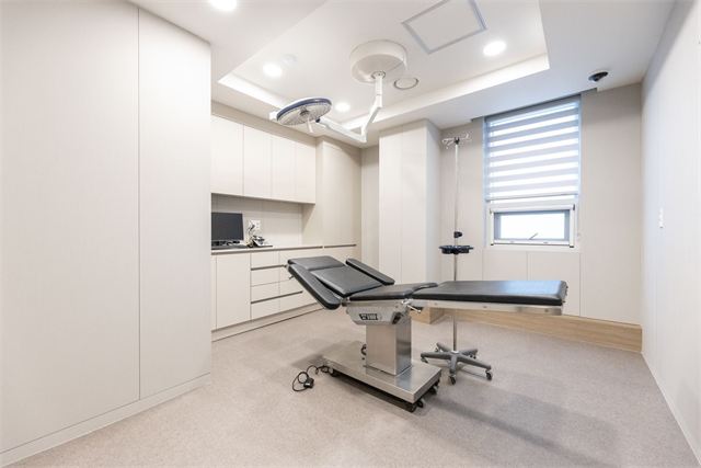Procedure room with an operating table and surgical light at Will Be Plastic Surgery