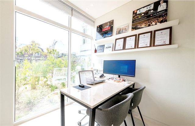 Second-floor consultation room with a desk, monitor and window at Yonsei Heal Dental Hospital