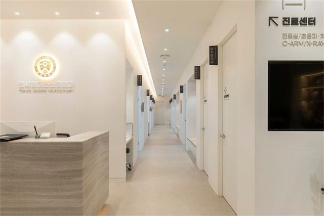 연세리더스신경외과의원 데스크와 벽면 사인, 진료실·C-ARM/X-RAY실로 이어지는 복도